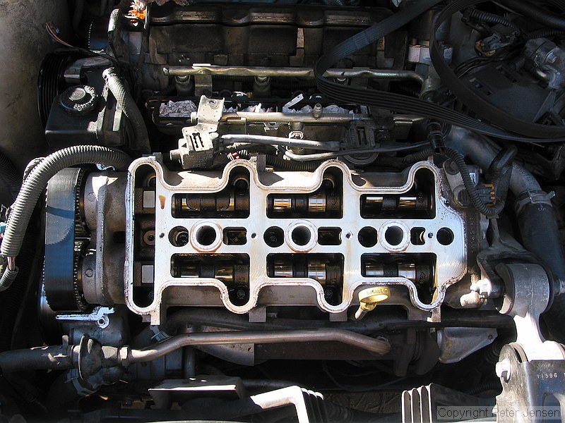 inside of a 1996 Chevrolet Lumina vin X 3.4L engine with the top bits removed while a neighbor changes the timing belt