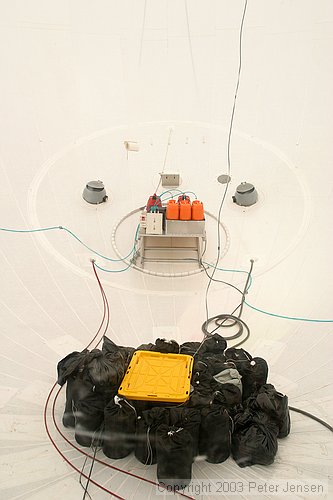 view through the window into the inner area of the ship showing pressurization fans, fuel system, and sandbags